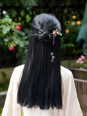Red bean Chinese hairpin worn on a half braided black hairstyle with beige Hanfu in a flowering garden