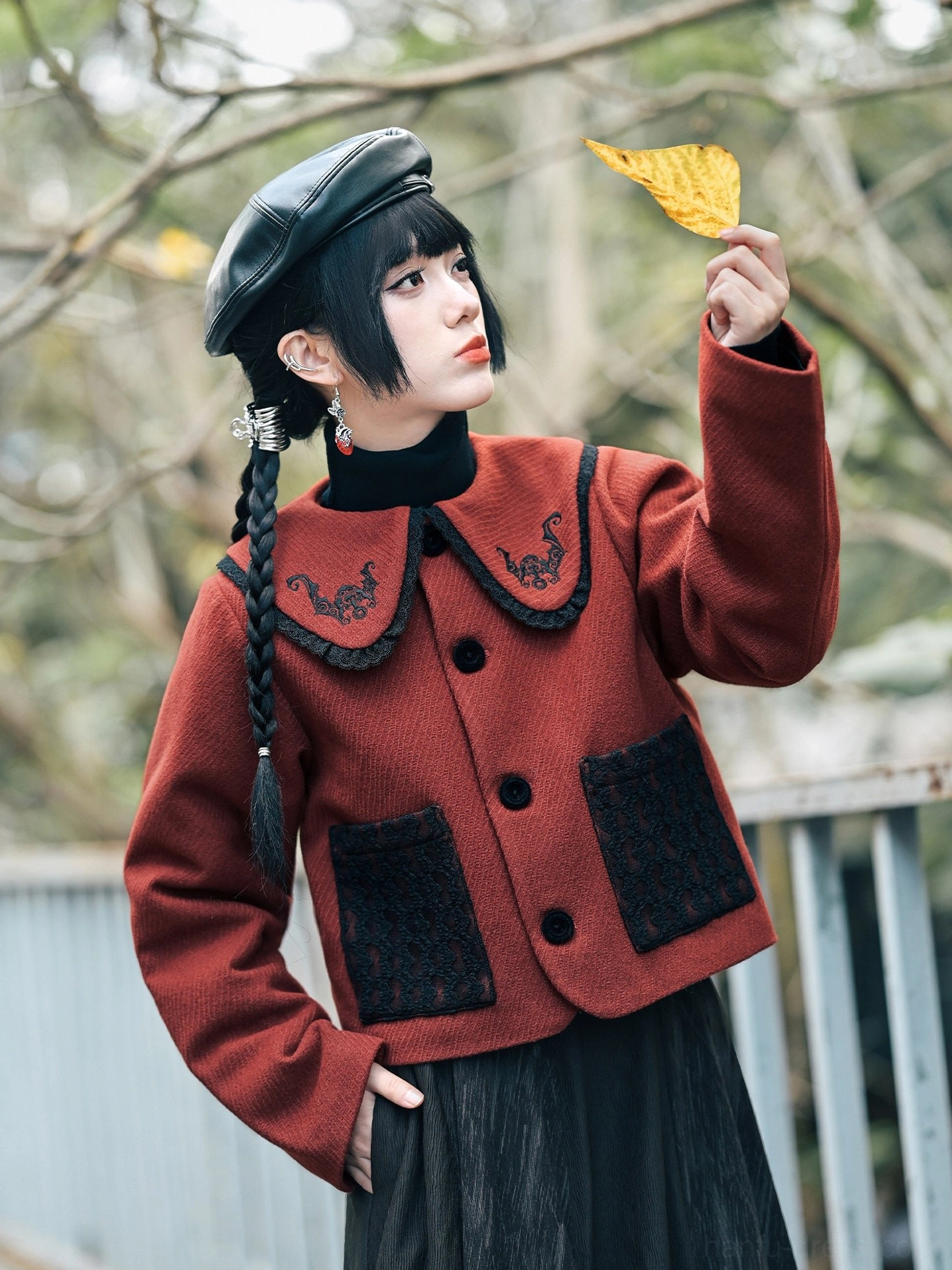 Three-quarter view of a brick red Chinese-style cropped Hanfu jacket showing the embroidered bat collar, button front, sleeve length, and tailored silhouette