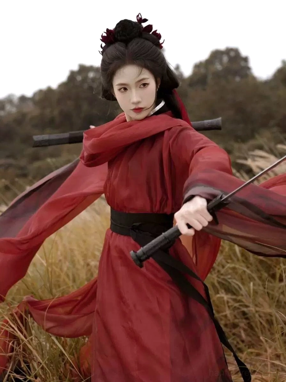 Dynamic front three-quarter view of a red and black Jin Dynasty warrior Hanfu with sheer wide sleeves, black waist sash, sword scabbard, and flowing fabric
