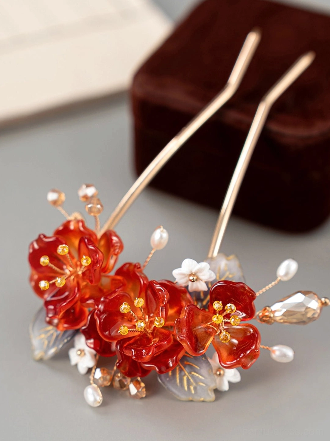 Close view of dual prong red blossom Hanfu hairpin with white flowers faux pearls smoky blue leaves and gold tone metal details