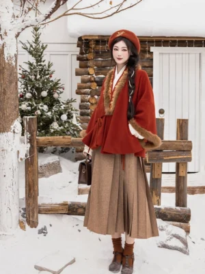 Red Chinese New Year Hanfu jacket and brown pleated mamian skirt worn as a festive winter outfit in a snowy yard