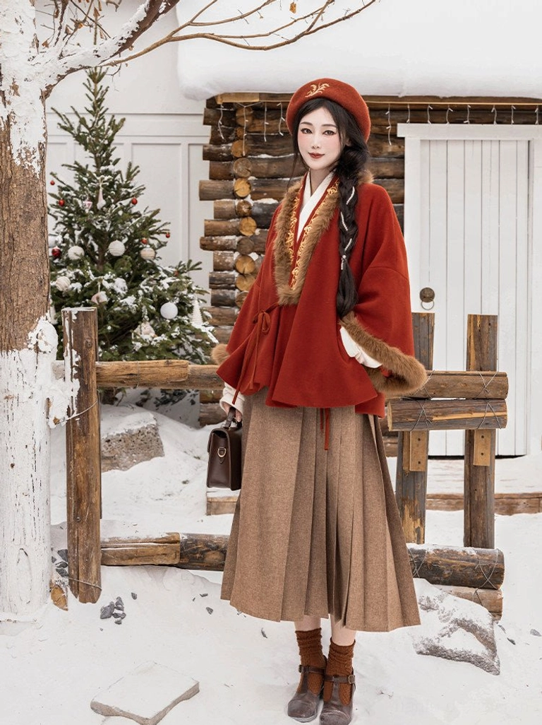 Red Chinese New Year Hanfu jacket and brown pleated mamian skirt worn as a festive winter outfit in a snowy yard