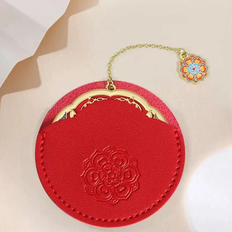 Red protective suede-style pouch for an auspicious Chinese pocket mirror, featuring an embossed traditional floral motif, stitched edges, and chain opening