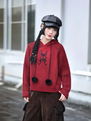 Front view of red Chinese style cropped hooded sweater with lucky bat embroidery, ribbed cuffs, ribbed hem, and black pom pom drawstrings