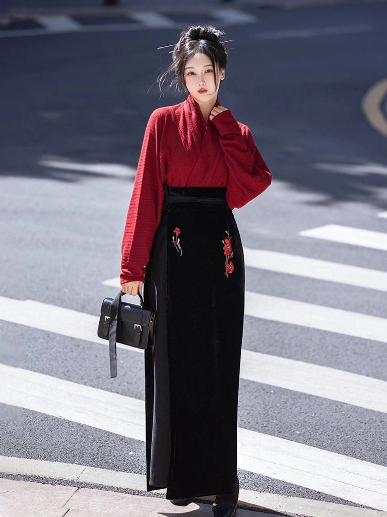 Close front view of textured red cross collar Hanfu top paired with a black floor length skirt featuring red flower embroidery