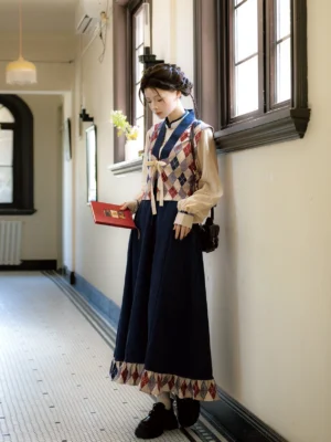 Modern Hanfu three piece outfit shown from the side with an off white lantern sleeve top, red and navy argyle vest, and dark blue A line skirt in a vintage apartment corridor