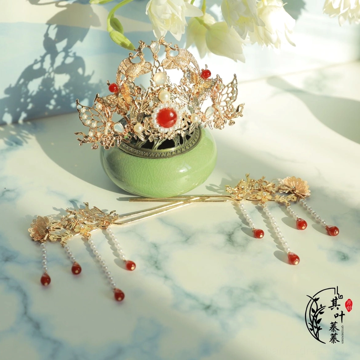 Red and gold Hanfu crown and tassel hairpins with central red gemstone pearl accents and dangling red beads shown in a three-quarter flat lay