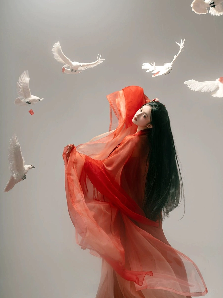 Side profile of a red gradient Tang Dynasty hanfu Qixiong Ruqun showing the sheer outer shawl, dramatic flowing fabric, elevated waistline, and elegant layered silhouette