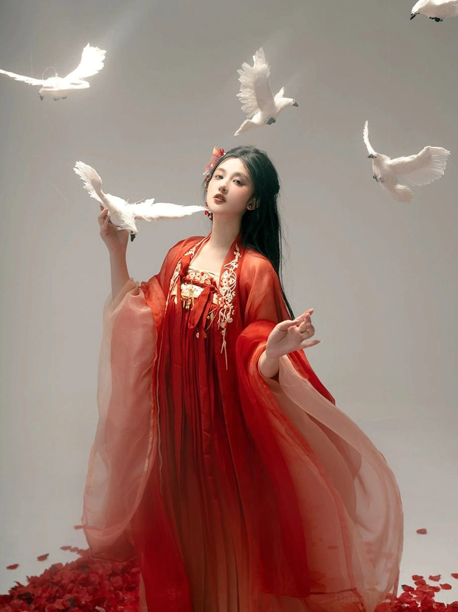 Close-up view of red gradient Tang style hanfu with intricate golden floral chest embroidery, sheer chiffon fabric, red flower hair accessory, and elegant layered details