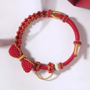 Red handwoven Chinese knot bow bracelet with auspicious knot ornaments, gold-tone adjustable hardware, and braided red cord