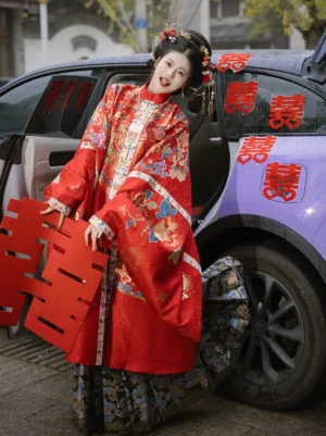 Red Ming Dynasty bridal Hanfu robe and Mamian skirt worn by a traditional Chinese bride beside a wedding car with double happiness decorations