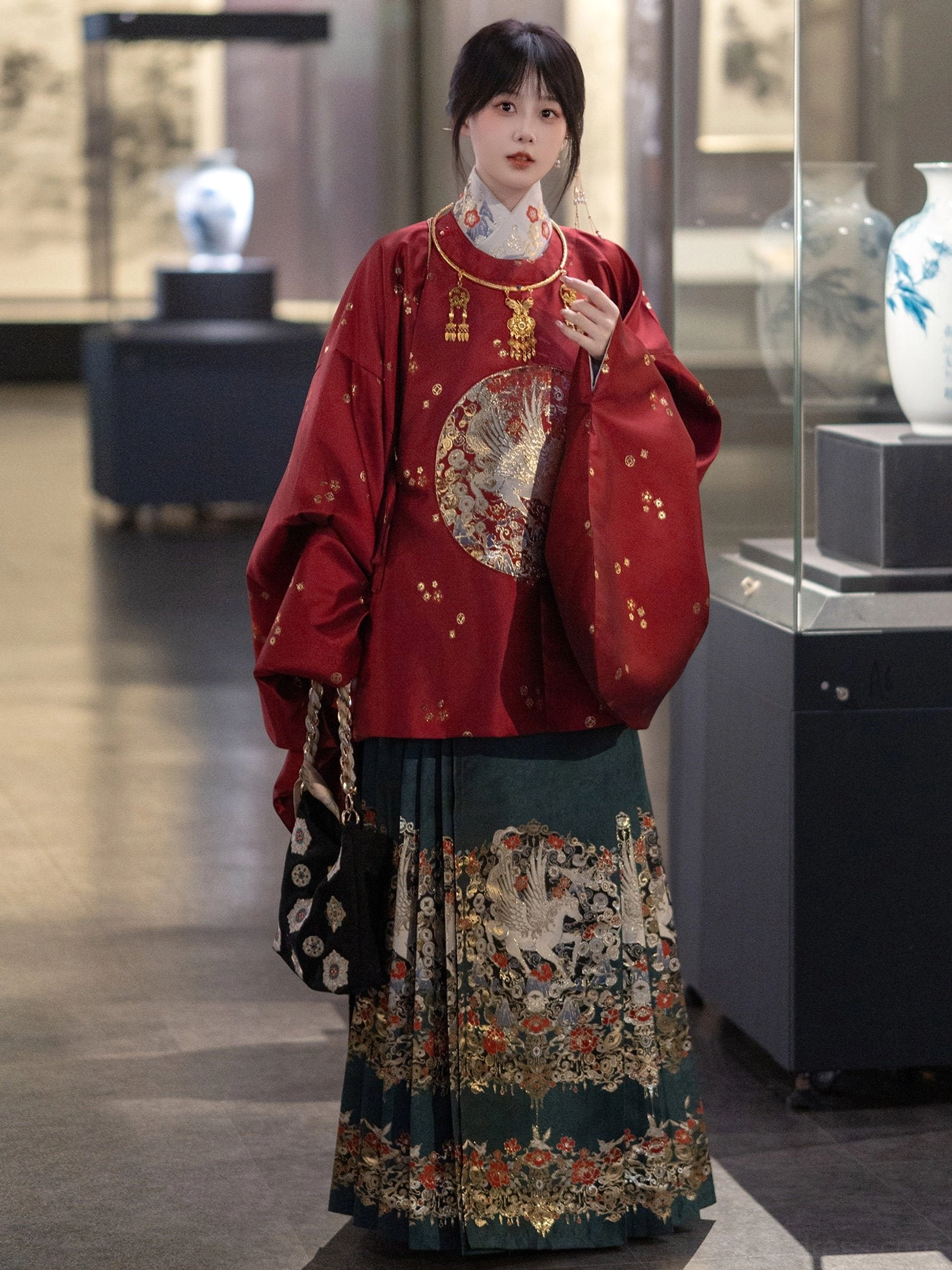 Red Ming-style Hanfu round-collar top with dark teal mamian skirt and gold floral embroidery side view