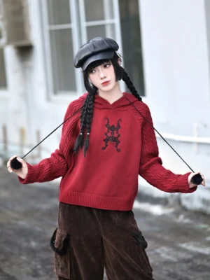 Red Modern Hanfu cropped hooded sweater with lucky bat 福蝠 embroidery, cable knit sleeves, and brown cargo pants in a three quarter outdoor portrait