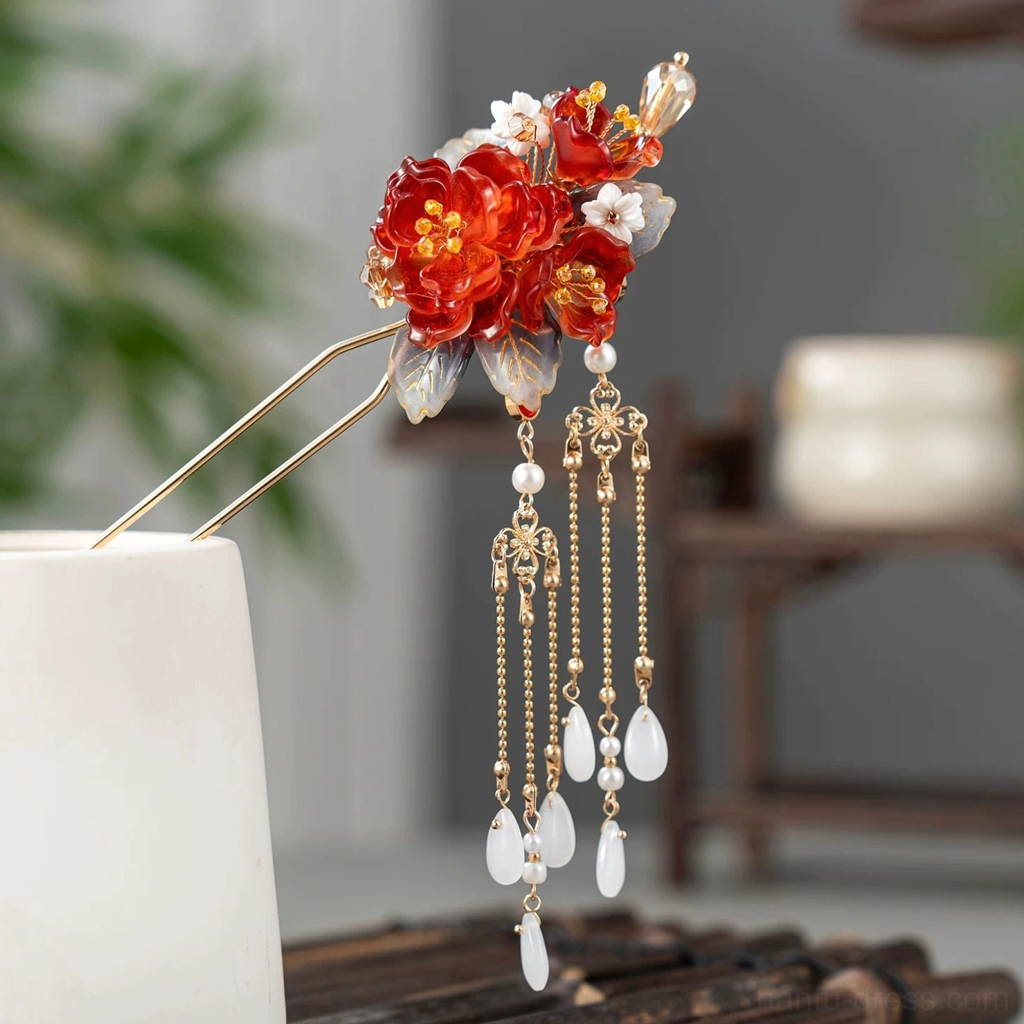 Simplified red peony Chinese hair stick with shorter tassel chains white teardrop pendant and floral ornament displayed on a ceramic holder