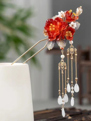 Red peony tassel Chinese hair stick displayed on a white ceramic holder with white flowers grey leaves gold-tone double prongs and long hanging pendants
