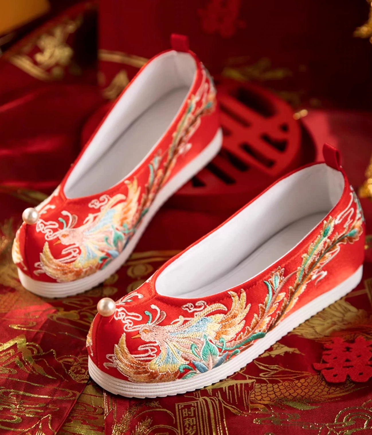 Red phoenix embroidered Chinese bridal Hanfu shoes with pearl toe ornament, white rubber sole, and traditional wedding styling