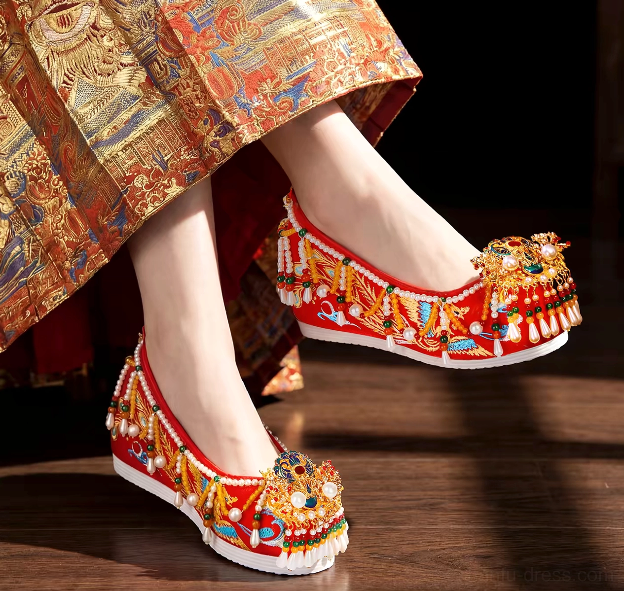 Red phoenix embroidered Chinese bridal Hanfu shoes worn with a gold embroidered wedding skirt, featuring pearl tassels, upturned toes, and white platform soles
