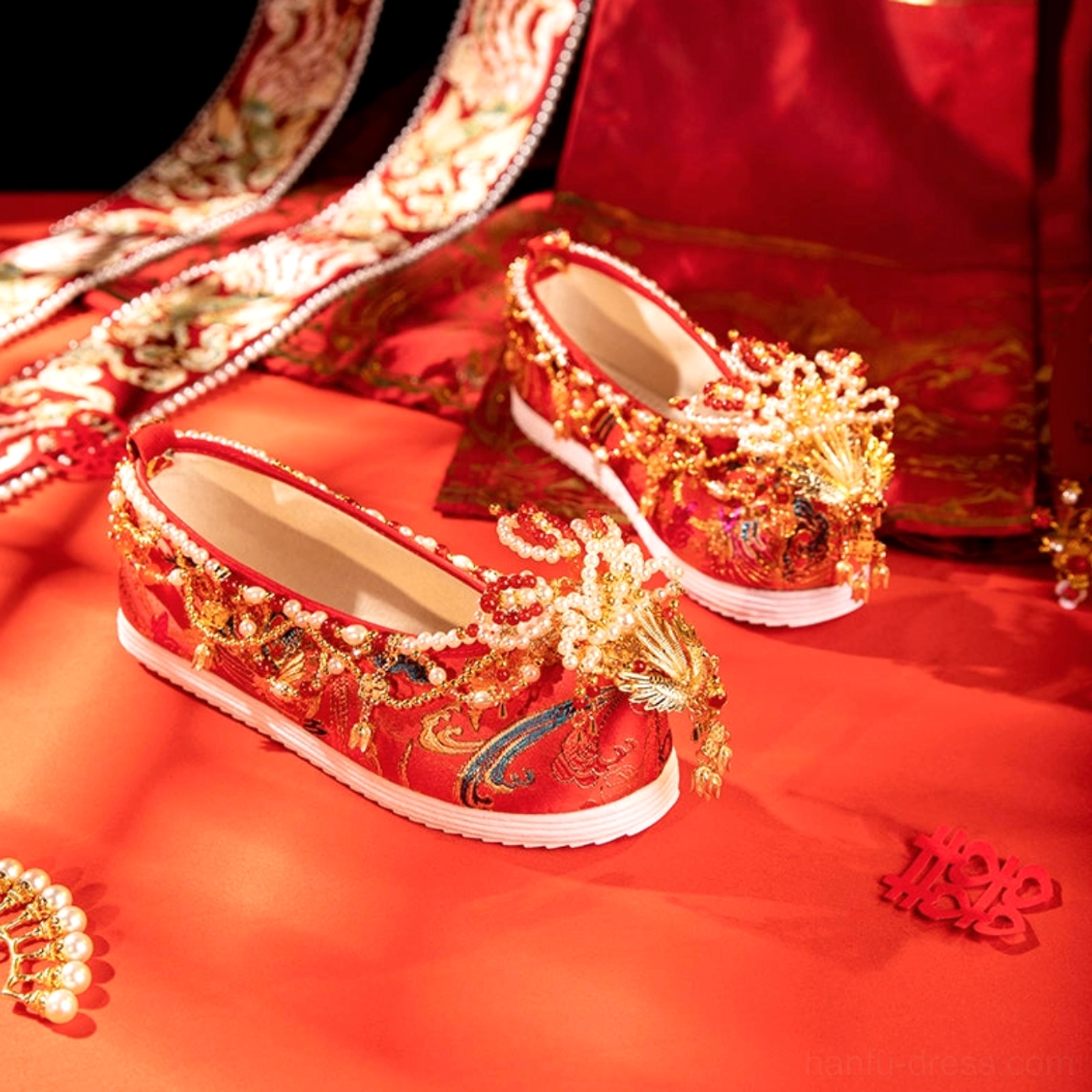 Red phoenix pearl bridal Hanfu shoes for Chinese wedding displayed on red satin with double happiness decoration