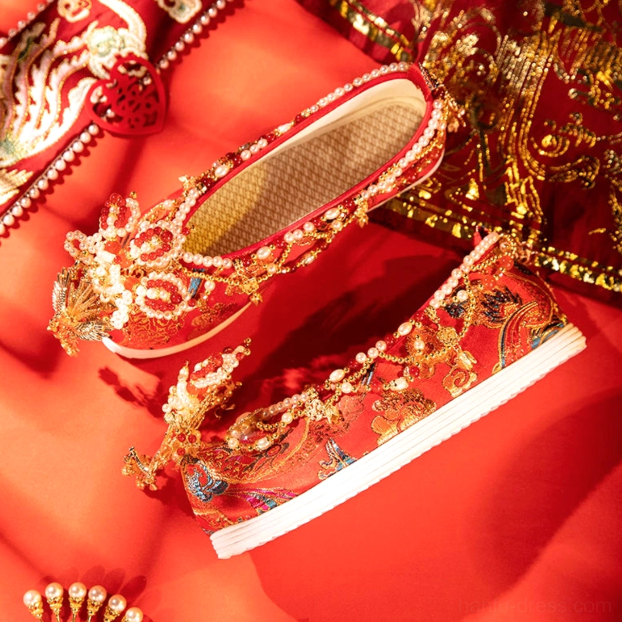 Overhead view of red Chinese bridal Hanfu shoes with gold embroidery pearl tassels mesh insole and white rubber sole