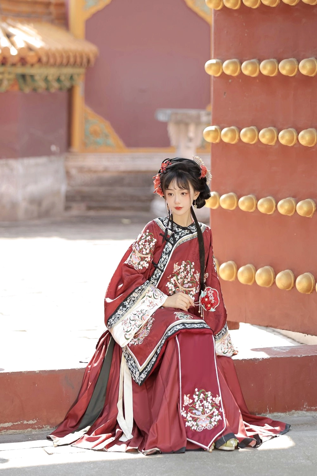 Full seated view of a red Qing Dynasty Han women's traditional blouse with floral embroidery, wide sleeves, and classic late Qing-inspired styling