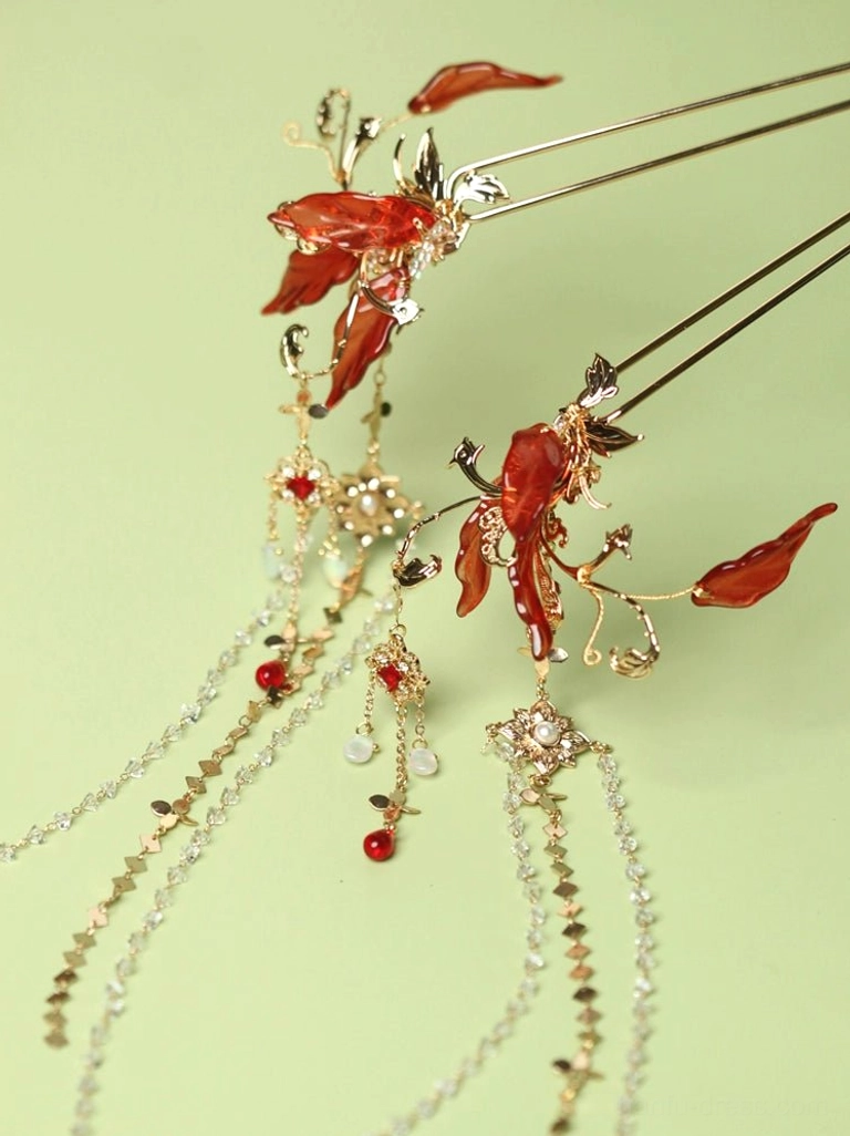 Pair of red spider lily Hanfu hair pins with gold-tone metal frames, red flower petals, crystal tassels, and red bead drops on a light green background
