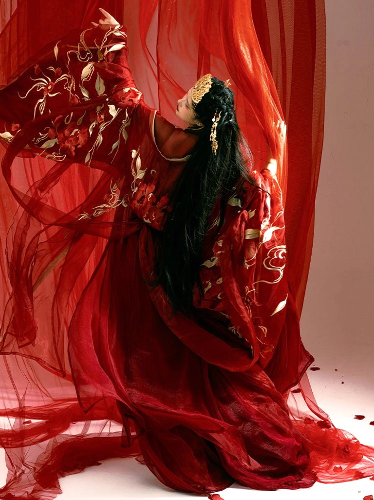 Back three-quarter view of a red Tang Dynasty Hanfu bridal dress showing flowing floor-length layers, ornate gold sleeve embroidery, decorated bodice, and golden Chinese hair accessories