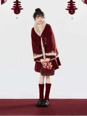 Smiling woman modeling a festive red Tang-inspired Hanfu outfit with embroidered deer and blessing motifs, wrap coat, mini horse-face skirt, red socks, and black loafers