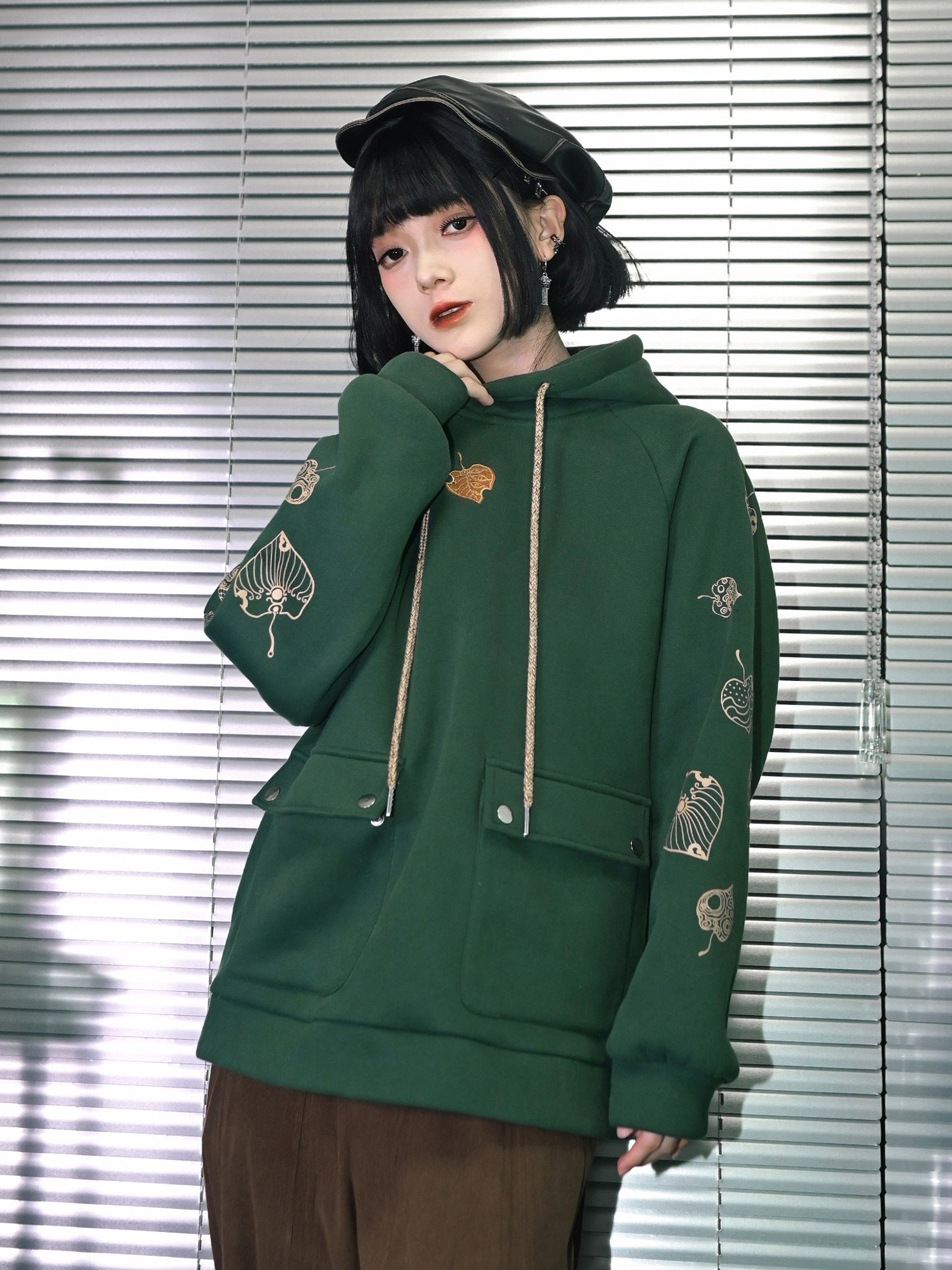 Three quarter view of Reincarnation dark green botanical embroidered hooded fleece sweatshirt showing golden sleeve embroidery and loose Modern Hanfu silhouette