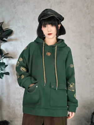 Front full body view of dark green Chinese style embroidered hoodie with golden leaf motifs on raglan sleeves, front patch pockets, and relaxed fit