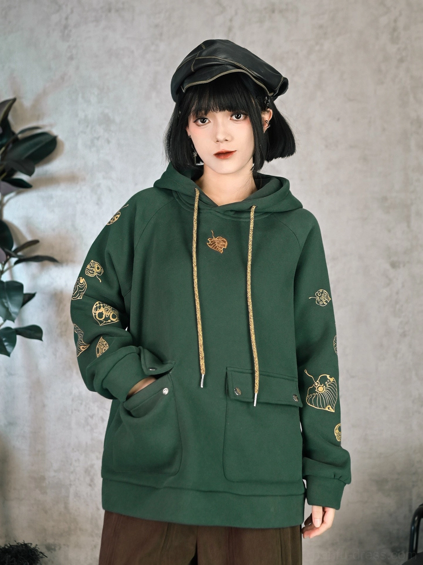 Front full body view of dark green Chinese style embroidered hoodie with golden leaf motifs on raglan sleeves, front patch pockets, and relaxed fit