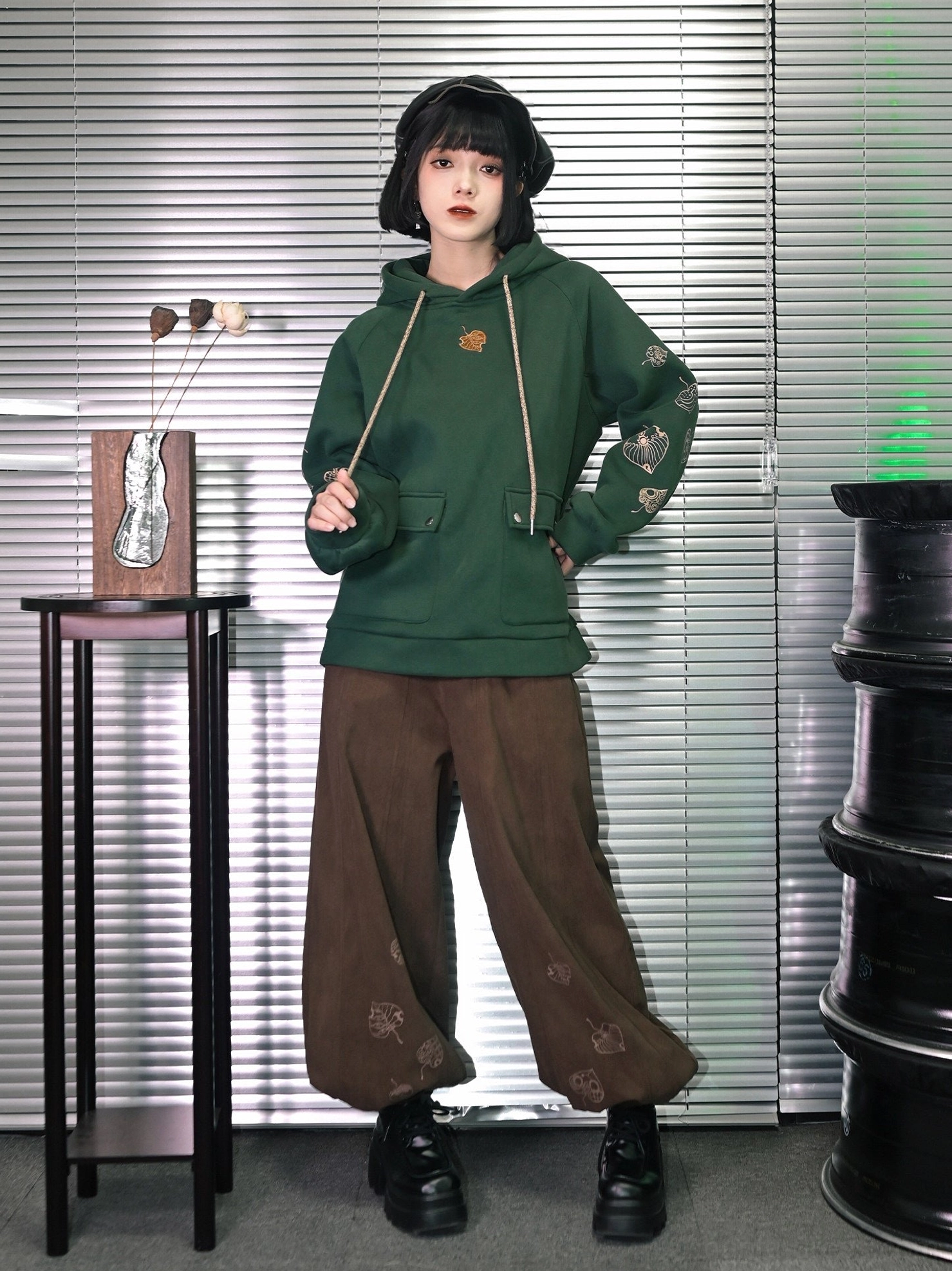 Side back full body view of dark green New Chinese style hooded sweatshirt with embroidered sleeves, front pockets, and relaxed vintage streetwear styling