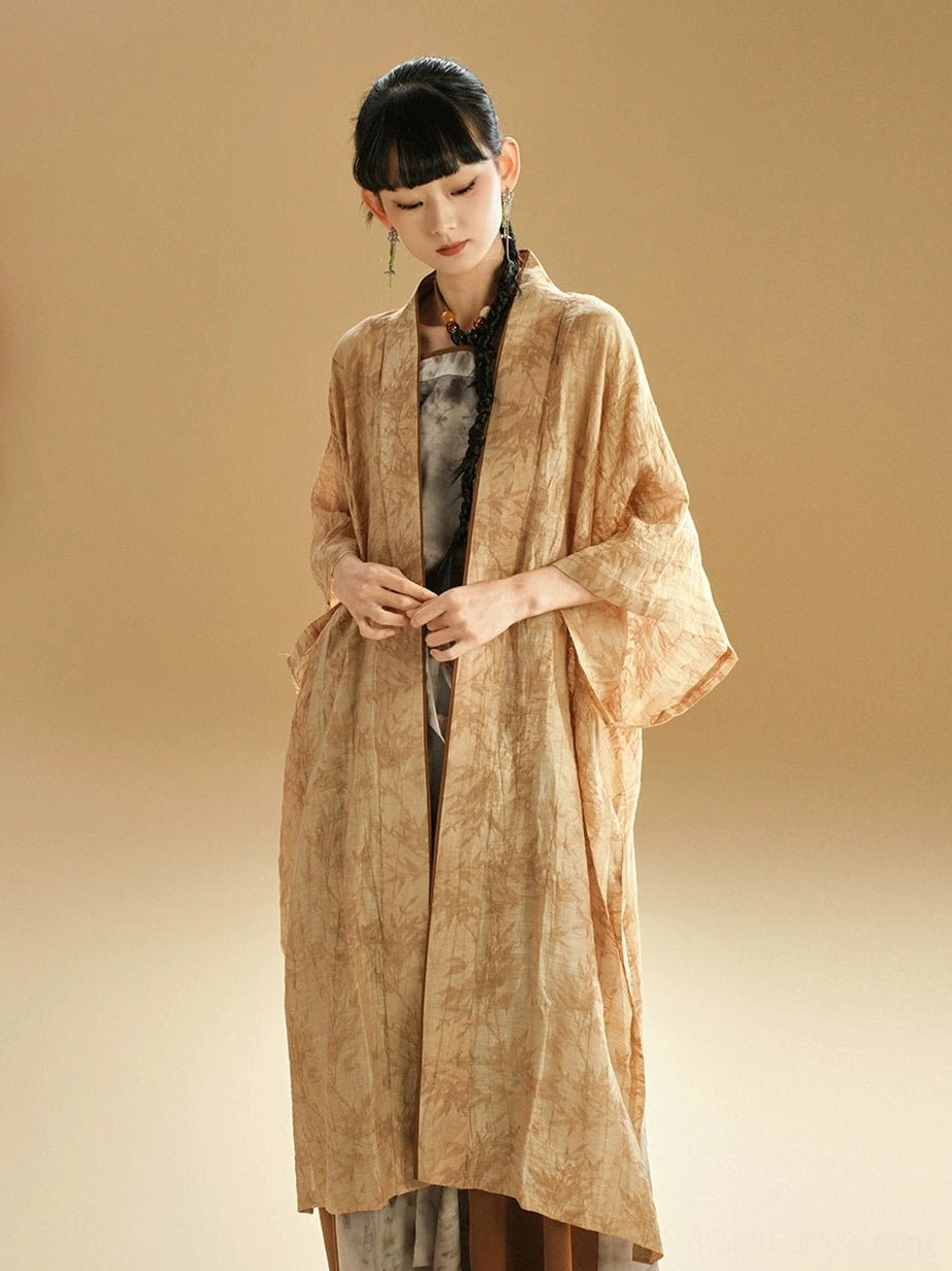 Waist-up front view of a woman wearing a relaxed modern Chinese Hanfu cardigan with an artistic earthy ink-wash pattern and layered outfit design