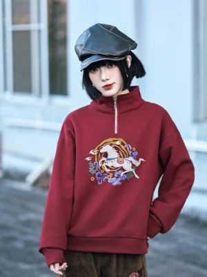 Close-up view of a retro Chinese-style burgundy fleece sweatshirt showing detailed horse and cloud chest embroidery, relaxed drop shoulders, long sleeves, and ribbed hem