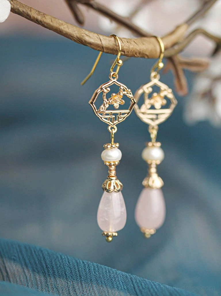 Retro pink pearl Chinese earrings with gold openwork window flower charms and pink teardrop pendants displayed on a dried flower branch