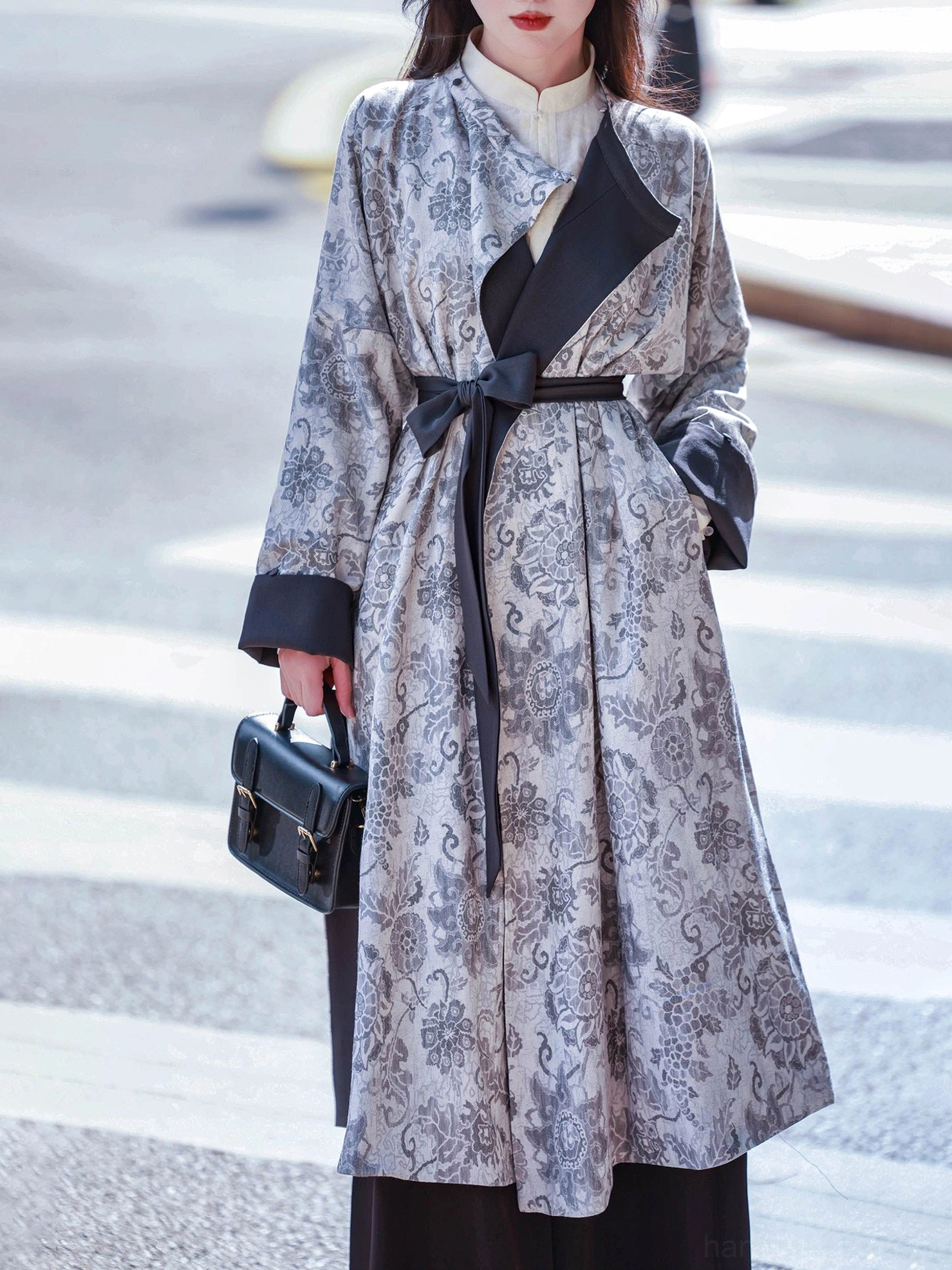 Close three-quarter view of a reversible floral print Hanfu round collar robe featuring black contrast lapel narrow waist sash and practical side pockets