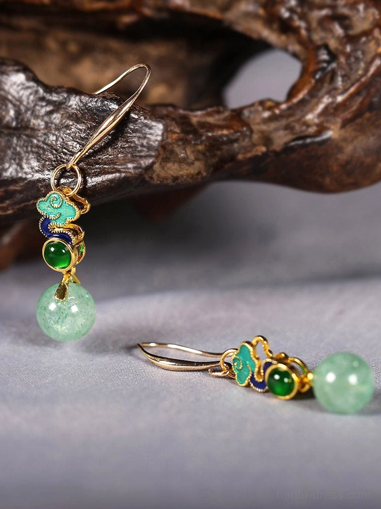 Close-up flat lay of Rising Clouds Chinese earrings showing gold ear wires, enamel-style cloud details, green cabochons, and pale green drop beads