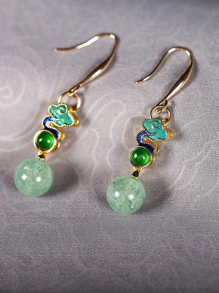Pair of Rising Clouds Chinese drop earrings on grey fabric featuring gold hooks, colorful cloud patterns, green stones, and pale green round beads