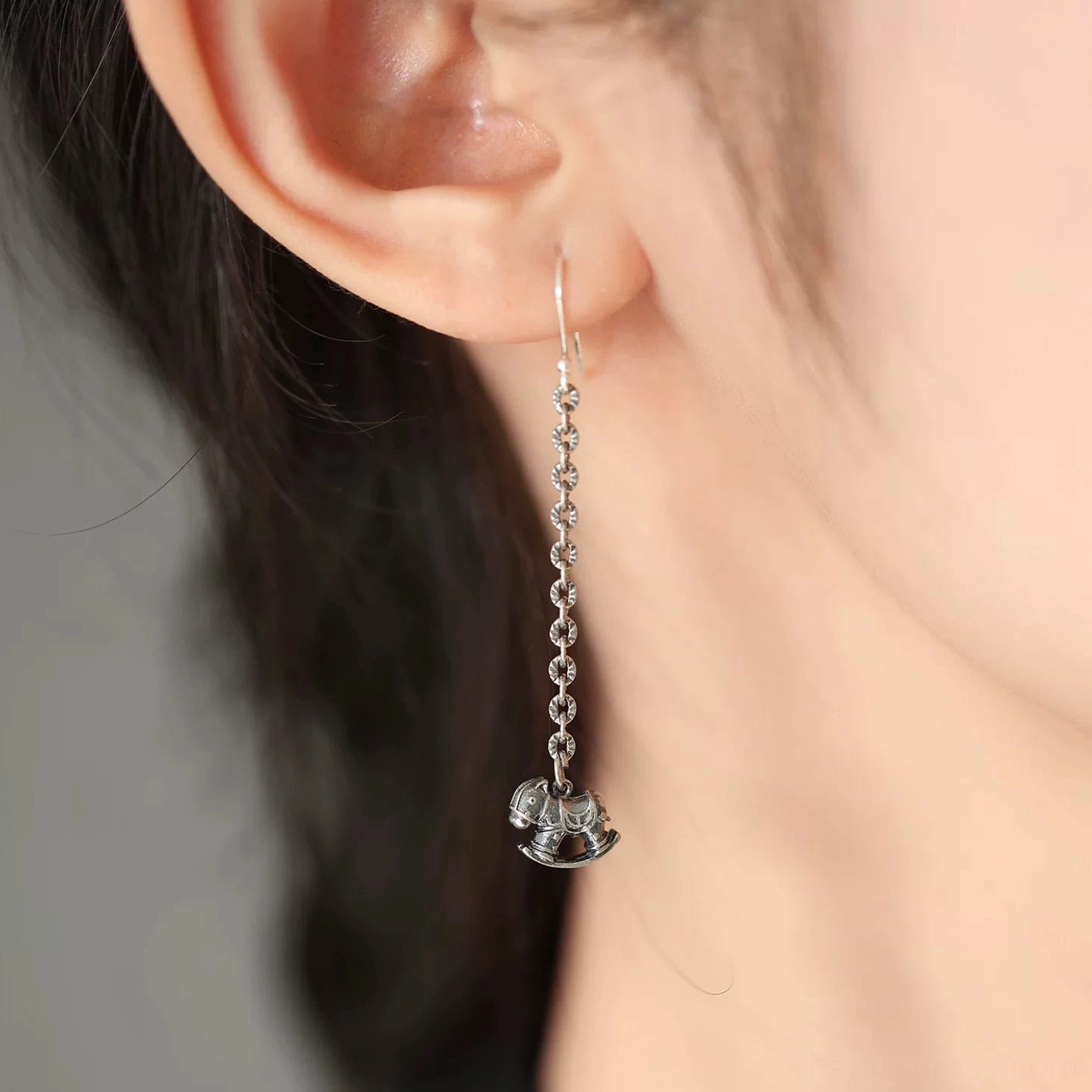 Long rocking horse drop earring shown worn on the ear, highlighting the elegant dangling silhouette and playful silver charm for Hanfu styling