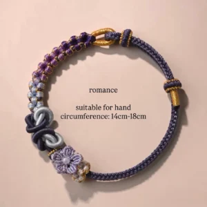 Romantic purple handwoven Chinese knot bracelet with gradient blue and purple cords, floral knot charm, and gold-tone details on a pink background