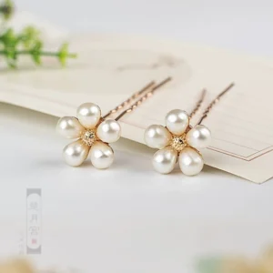 Rose gold imitation pearl flower hair pins shown as a matching pair on vintage Chinese style paper with green leaf decoration