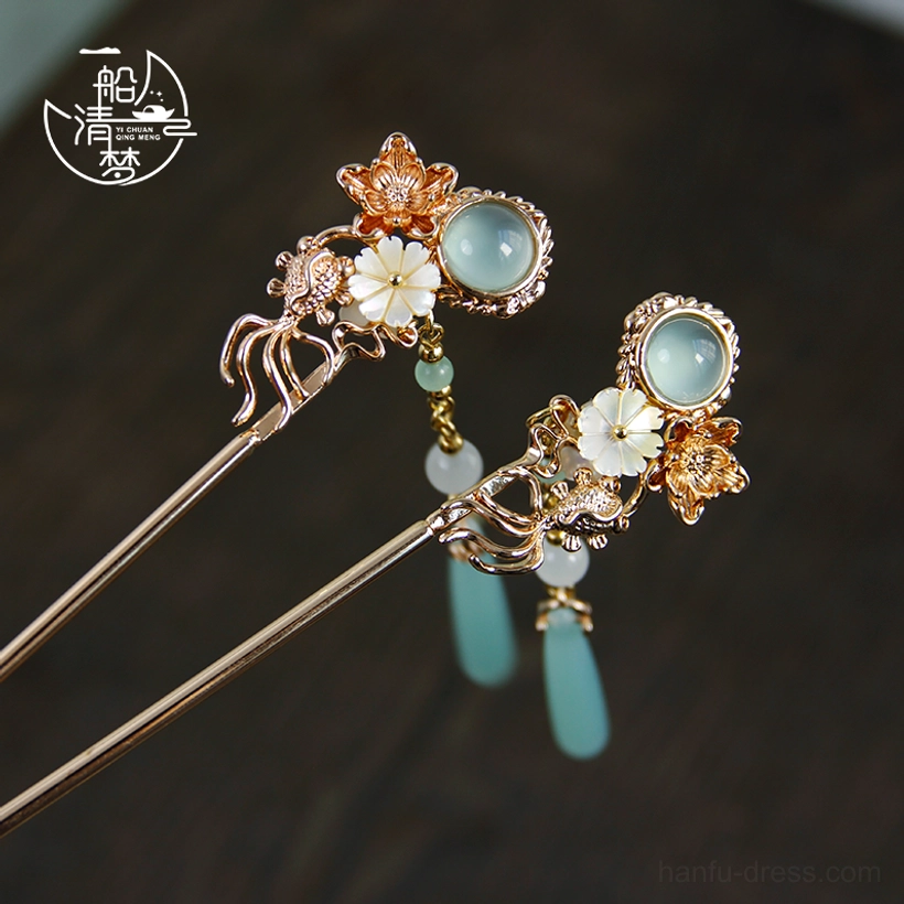 Rose gold tone Chinese hair sticks with white shell flowers and light blue jade style decorative stones on dark wooden surface