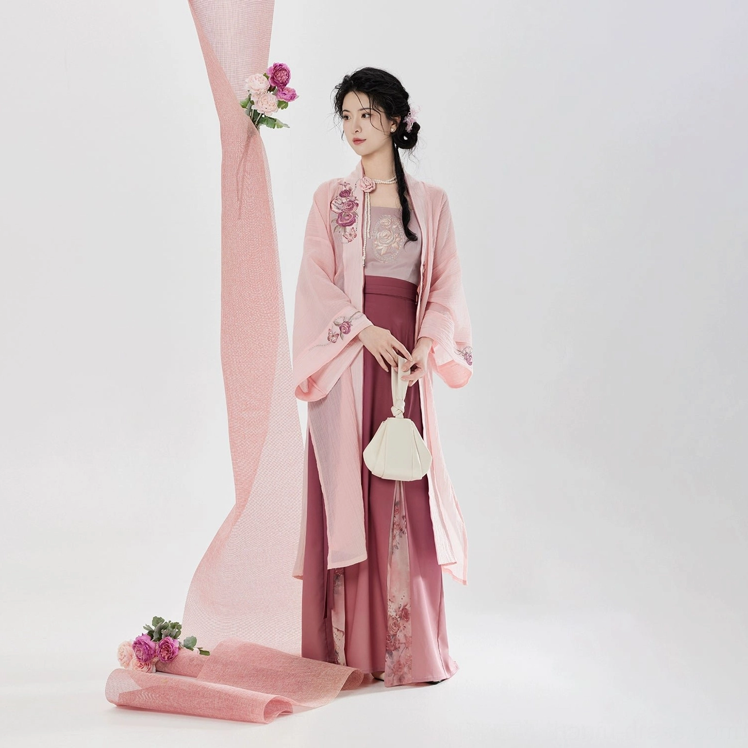 Front three quarter view of Song Dynasty modern hanfu set with embroidered pink beizi jacket layered camisole and three pleat wrap skirt