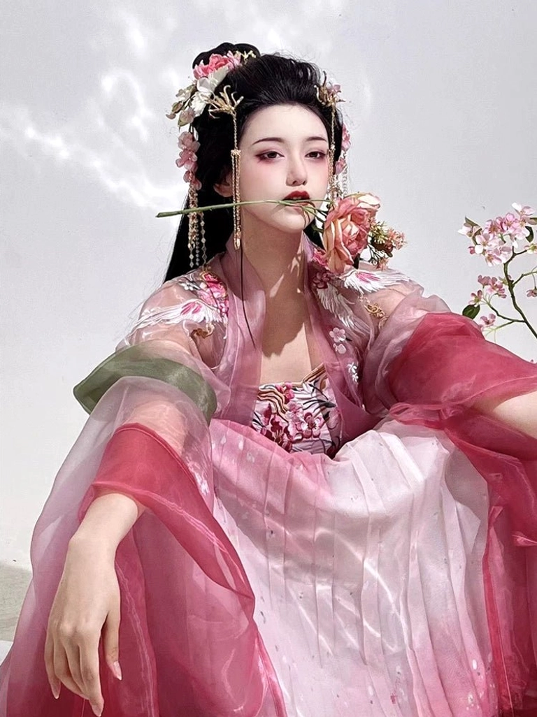 Close-up upper body view of rose pink Heziqun Hanfu with embroidered bust detail, green shoulder sash, traditional hairstyle, and delicate Chinese-inspired makeup