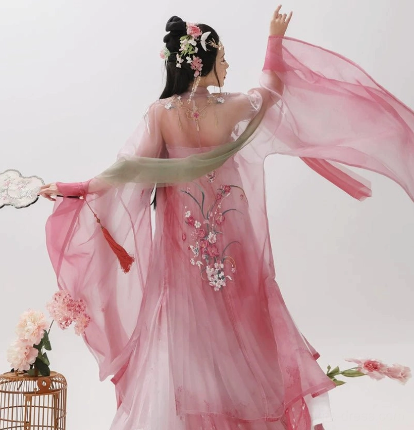 Back dancing view of a rose pink Tang Dynasty Hanfu coat with fluttering sheer wide sleeves, floral back embroidery, green sash, and traditional round fan