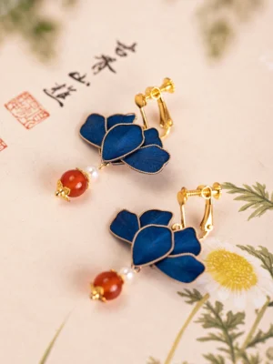 Royal blue lotus Chinese earrings with gold clip-on fittings, red agate-style beads and pearl accents on traditional calligraphy background