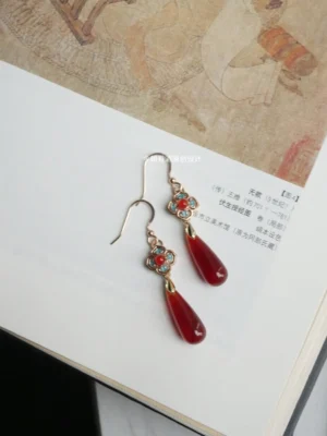 Chinese flower drop earrings with ruby red teardrop pendants and blue decorative accents displayed on a traditional painting album page