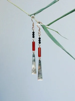 Ruby red shell drop Chinese earrings with black beads and gold hooks displayed beside green bamboo branches for Hanfu jewelry styling