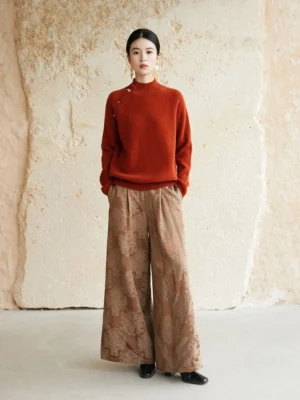 Full-body front view of a rust red modern Hanfu wool sweater with mock neck and Chinese frog buttons styled with floral wide-leg trousers