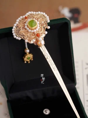 Ruyi style vintage Chinese gold Hanfu hairpin with green jade accent pearl tassel red beads and intricate filigree head displayed in a dark green velvet jewelry box