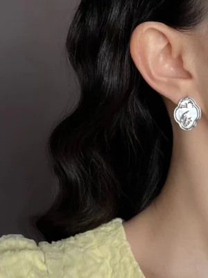 Woman wearing ruyi mother-of-pearl pavilion stud earrings with silver-tone Chinese-inspired Hanfu jewelry detail